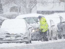 A person cleans off a car during a winter snow storm in Philadelphia, Tuesday, Feb. 13, 2024. (AP Photo/Matt Rourke)