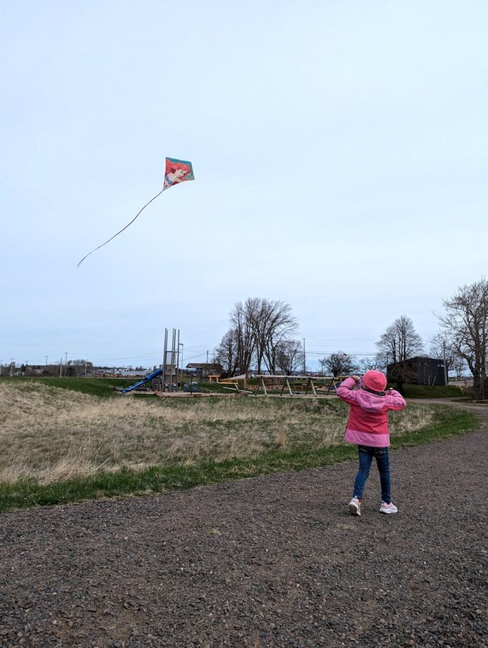 girl in jacket and flying kite