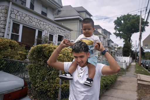 Migrant Darwin Salinas walks with his 1-year-old son Derek, Sunday, June 16, 2024, in Irvington, N.J. Thousands of migrant families in New York City are facing a summer of uncertainty for their school-aged children with a citywide limit of 60 days in a shelter before needing to reapply or find their own. (AP Photo/Andres Kudacki)