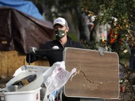 FILE - California Gov. Gavin Newsom helps clean a homeless encampment alongside a freeway, Wednesday, Jan. 12, 2022, in San Diego. Newsom issued an executive order Thursday, July 25, 2024, for the removal of homeless encampments in the state. (AP Photo/Gregory Bull, File)