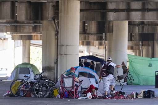 People living in a homeless encampment pick up belongings after Louisiana State police gave instructions for them to move to a different pre-designated location as they perform a sweep in advance of a Taylor Swift concert in New Orleans, Wednesday, Oct. 23, 2024. (AP Photo/Gerald Herbert)