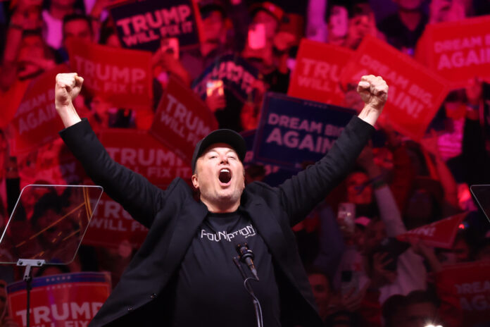 NEW YORK, NEW YORK - OCTOBER 27: Tesla and X CEO Elon Musk raises his hands as he takes the stage during a campaign rally for Republican presidential nominee, former U.S. President Donald Trump, at Madison Square Garden on October 27, 2024 in New York City. Trump closed out his weekend of campaigning in New York City with a guest list of speakers that includes his running mate Republican Vice Presidential nominee, U.S. Sen. J.D. Vance (R-OH), Tesla CEO Elon Musk, UFC CEO Dana White, and House Speaker Mike Johnson, among others, nine days before Election Day. (Photo by Michael M. Santiago/Getty Images)