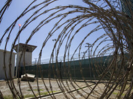 FILE - In this April 17, 2019, photo, reviewed by U.S. military officials, the control tower is seen through the razor wire inside the Camp VI detention facility in Guantanamo Bay Naval Base, Cuba. (AP Photo/Alex Brandon, File)