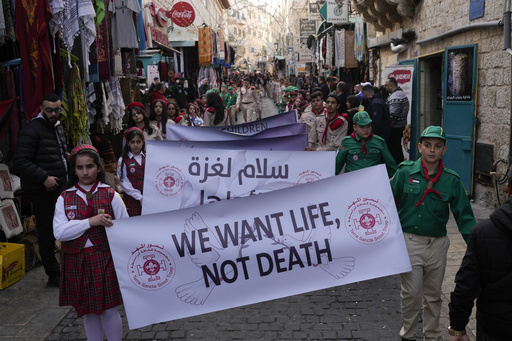 Scouts hold a sign that reads "We want life, not death" during the traditional Christian procession towards the Church of the Nativity, traditionally believed to be the birthplace of Jesus, on Christmas Eve, in the West Bank city of Bethlehem, Tuesday, Dec. 24, 2024. (AP Photo/Matias Delacroix)