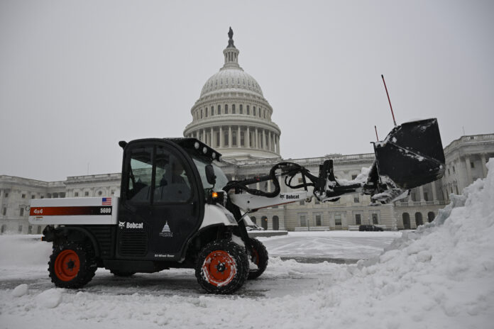 A front end loader clears a heavy early morning snow fall on the east side of the Capitol ahead of a joint session of Congress to certify the votes from the Electoral College in the presidential election, Monday, Jan. 6, 2025, in Washington. (AP Photo/John McDonnell)