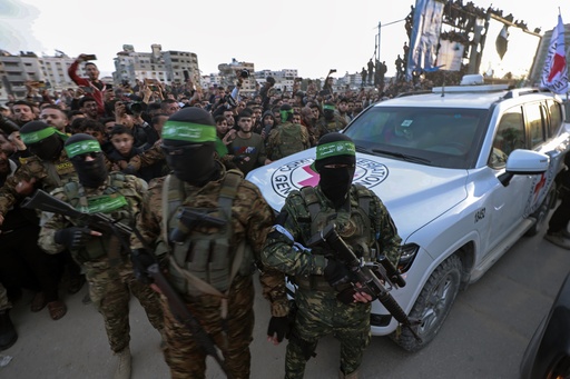 Hamas fighters escort a Red Cross vehicle to collect Israeli hostages released after a ceasefire agreement between Israel and Hamas took effect, in Gaza City Sunday, Jan. 19, 2025. (AP Photo/Abed Hajjar)