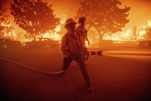 Firefighters battle the Palisades Fire as it burns multiple structures in the Pacific Palisades neighborhood of Los Angeles, Tuesday, Jan. 7, 2025. (AP Photo/Ethan Swope)