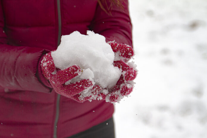 Close-up of hands in mittens holding snowball