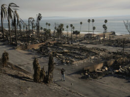 A person walks past damage from the Palisades Fire