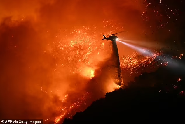 A fire fighting helicopter drops water during the Palisades fire

