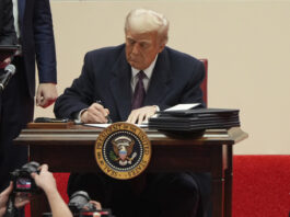 President Donald Trump signs an executive order at an indoor Presidential Inauguration parade event in Washington, Monday, Jan. 20, 2025. (AP Photo/Matt Rourke)