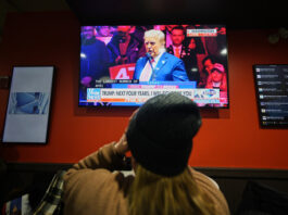 A woman watches President-elect Donald Trump speak at a rally ahead of the 60th Presidential Inauguration, Sunday, Jan. 19, 2025, in Washington. (AP Photo/Mike Stewart)