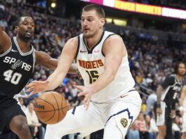 Denver Nuggets center Nikola Jokic, front, collects a loose ball as San Antonio Spurs forward Harrison Barnes defends in the first half of an NBA basketball game Friday, Jan. 3, 2025, in Denver. (AP Photo/David Zalubowski)