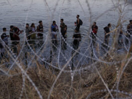 FILE - Migrants wait to climb over concertina wire after they crossed the Rio Grande and entered the U.S. from Mexico on Sept. 23, 2023, in Eagle Pass, Texas. (AP Photo/Eric Gay, File)