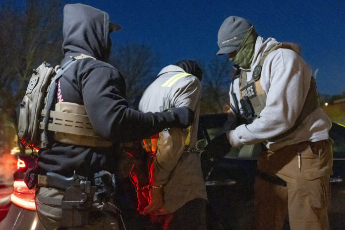 U.S. Immigration and Customs Enforcement officers use a chain to more comfortably restrain a detained person using handcuffs positioned in front, Monday, Jan. 27, 2025, in Silver Spring, Md. (AP Photo/Alex Brandon)