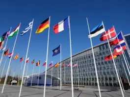 An empty flagpole for Finland stands between the national flags of France and Estonia outside NATO headquarters in Brussels shortly before Finland met all the requirements to join the alliance [File: Virginia Mayo/AP]