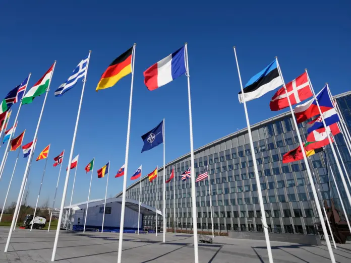 An empty flagpole for Finland stands between the national flags of France and Estonia outside NATO headquarters in Brussels shortly before Finland met all the requirements to join the alliance [File: Virginia Mayo/AP]