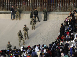 FILE - Migrants congregate on the banks of the Rio Grande at the U.S. border with Mexico on Dec. 20, 2022, where members of the Texas National Guard cordoned off a gap in the U.S. border wall. (AP Photo/Morgan Lee)