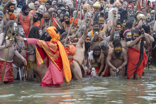 Naked Hindu ascetics and holy men immerse an idol before bathing at the confluence of the Ganges, the Yamuna and the mythical Saraswati rivers on the second day of the 45-day-long Maha Kumbh festival in Prayagraj, India, Tuesday, Jan. 14, 2025. (AP Photo/Ashwini Bhatia)