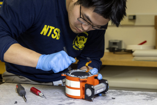 In this image provided by the National Transportation Safety Board, a NTSB investigator examine cockpit voice recorder and flight data recorder in Washington, Thursday, Jan. 30, 2025, recovered from the American Airlines passenger jet that crashed with an Army helicopter Wednesday night near Ronald Reagan Washington National Airport. (NTSB via AP)