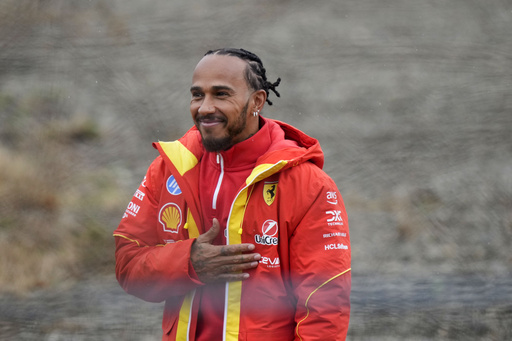 Lewis Hamilton greets supporters while taking the wheel of a Ferrari F1 vehicle for the inaugural time.