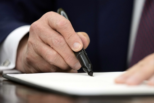 President Donald Trump signs an executive order in the Oval Office of the White House, Thursday, Jan. 23, 2025, in Washington. (AP Photo/Ben Curtis)