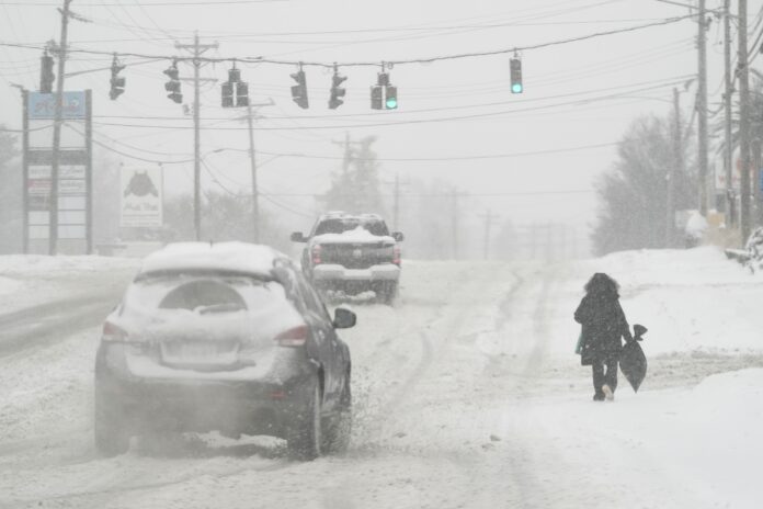 FILE - Heavy snow falls as a person walks along U.S. Route 42 in Florence, Ky., Monday, Jan. 6, 2025. (AP Photo/Carolyn Kaster, File)