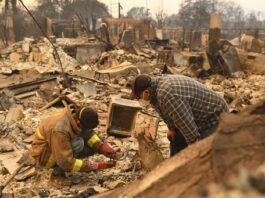 Robert Lara, left, looks for belongings along with his stepfather after the Eaton Fire burns in Altadena, Calif., Thursday, Jan. 9, 2025. (AP Photo/Nic Coury)