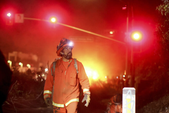 A California Department of Corrections hand crew works containment lines ahead of the Palisades Fire Tuesday, Jan. 14, 2025 in Santa Monica, Calif. (AP Photo/Ethan Swope)