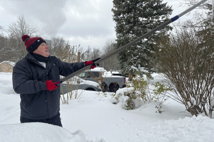 FILE - Resident Todd Brainard cleans snow off of the roof of his home in North Perry, Ohio on Tuesday, Dec. 3, 2024. (AP Photo/Patrick Aftoora-Orsagos, File)