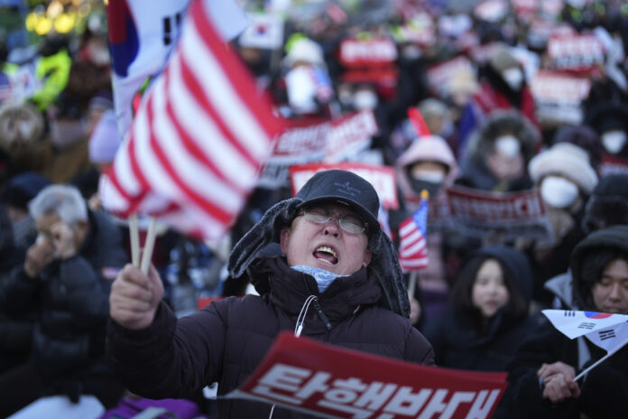 Supporters of impeached South Korean President Yoon Suk Yeol stage a rally to oppose a court having issued a warrant to detain Yoon, near the presidential residence in Seoul, South Korea, Friday, Jan. 3, 2025. The letters read, 