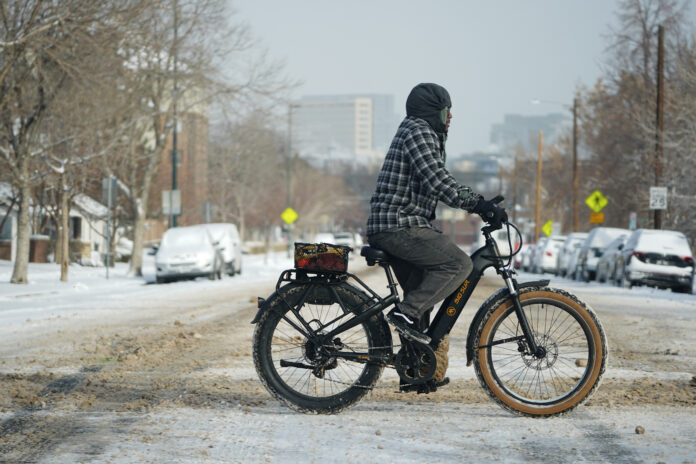 A cyclist navigates 13th Avenue after a winter storm plunged daytime high temperatures into the single digits and left up to six inches of snow in its wake Monday, Jan. 20, 2025, in Denver. (AP Photo/David Zalubowski)