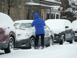 A motorist clears ice and snow from the windshield of a vehicle as a winter storm sweeps over the intermountain West, plunging temperatures into the single digits and bringing along a light snow in its wake Saturday, Jan. 18, 2025, in Denver. (AP Photo/David Zalubowski)