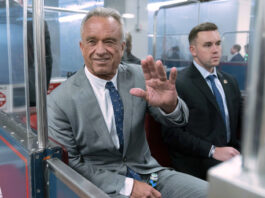 FILE - Robert F. Kennedy Jr., waves to reporters as he rides the train to go to meet with Sen. John Thune, R-S.D. at the Capitol in Washington, Dec. 17, 2024. (AP Photo/Jose Luis Magana, File)