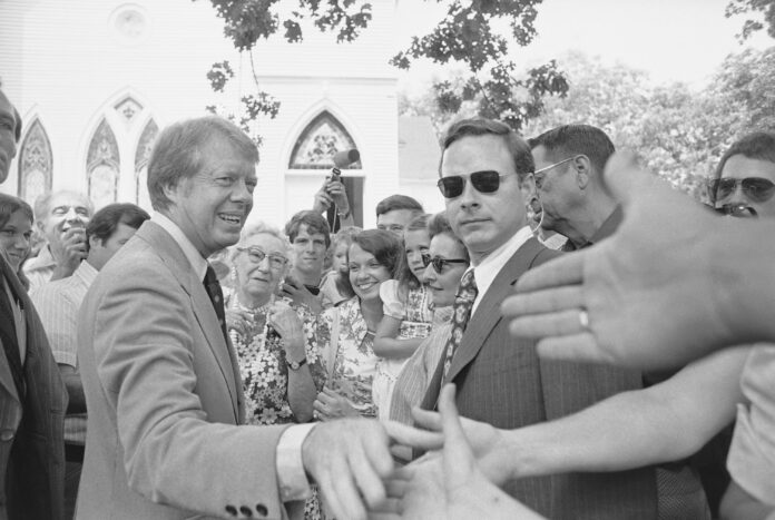 FILE - Democratic nominee Jimmy Carter shakes hands with church-goers outside the Plains Baptist Church, in Plains, Ga., on July 18, 1976. (AP Photo/Peter Bregg, File)