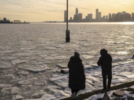 People walk along the pier as ice floats on the Hudson River, Thursday, Jan. 23, 2025, in New York. (AP Photo/Yuki Iwamura)