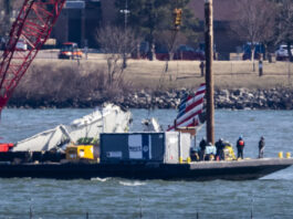 Parts of a plane are lifted from the water near the wreckage site in the Potomac River of a mid-air collision between an American Airlines jet and a Black Hawk helicopter, at Ronald Reagan Washington National Airport, Tuesday, Feb. 4, 2025, in Arlington, Va. (AP Photo/Ben Curtis)