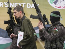 Israeli captive Or Levy, who has been held hostage by Hamas in Gaza since October 7, 2023, is escorted by Hamas fighters before being handed over to the Red Cross in Deir al-Balah, central Gaza Strip, Saturday Feb. 8, 2025. (AP Photo/Abdel Kareem Hana)