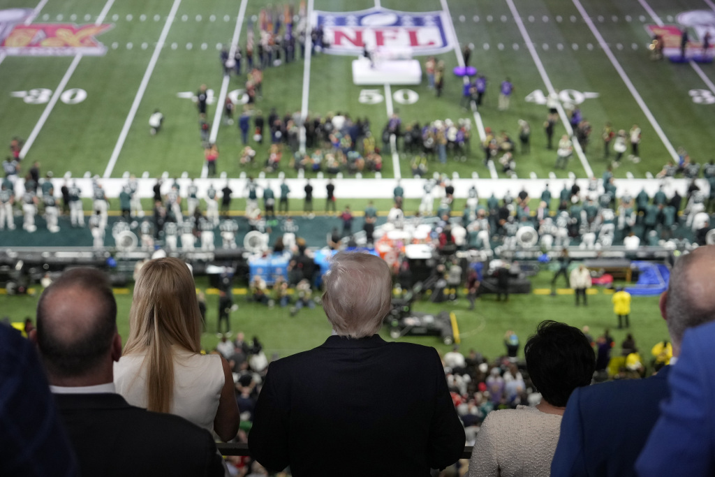 President Donald Trump, center, listens as Jon Batiste performs the national anthem at the NFL Super Bowl 59 football game between the Philadelphia Eagles and the Kansas City Chiefs, Sunday, Feb. 9, 2025, in New Orleans. (AP Photo/Ben Curtis)