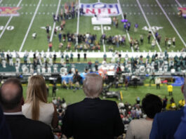 President Donald Trump, center, listens as Jon Batiste performs the national anthem at the NFL Super Bowl 59 football game between the Philadelphia Eagles and the Kansas City Chiefs, Sunday, Feb. 9, 2025, in New Orleans. (AP Photo/Ben Curtis)