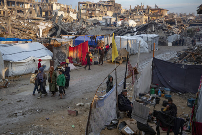 Palestinians walk along a street amid widespread destruction caused by the Israeli military's ground and air offensive against Hamas in Gaza City's Jabaliya refugee camp, Tuesday, Feb. 11, 2025. (AP Photo/Jehad Alshrafi)