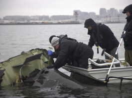 In this undated image provided by the National Transportation Safety Board, NTSB investigators and members of the salvage crew recover wreckage from the Army Black Hawk helicopter that collided with an American Airlines jet Wednesday night, Jan. 29, 2025, near Ronald Reagan Washington National Airport in Arlington, Va. (NTSB via AP)