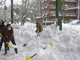 People remove snow from a street in Kushiro, Hokkaido, Japan, Tuesday, Feb. 4, 2025. (Kyodo News via AP)