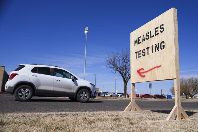 A vehicle drives past a sign outside of Seminole Hospital District offering measles testing Friday, Feb. 21, 2025, in Seminole, Texas. (AP Photo/Julio Cortez)