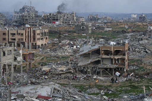 Palestinians stand next to a fire beside a destroyed house in an area littered with rubble from buildings destroyed during the Israeli army's ground and air offensive against Hamas, in Gaza City, Tuesday Feb. 4, 2025.(AP Photo/Abdel Kareem Hana)