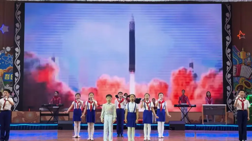 North Korean schoolchildren perform against a backdrop of ballistic missiles in flight.
YouTube / Mike Okay